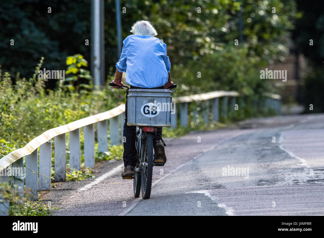 Male riding a bicycle on a country lane with G.B. sticker. Stock Photo