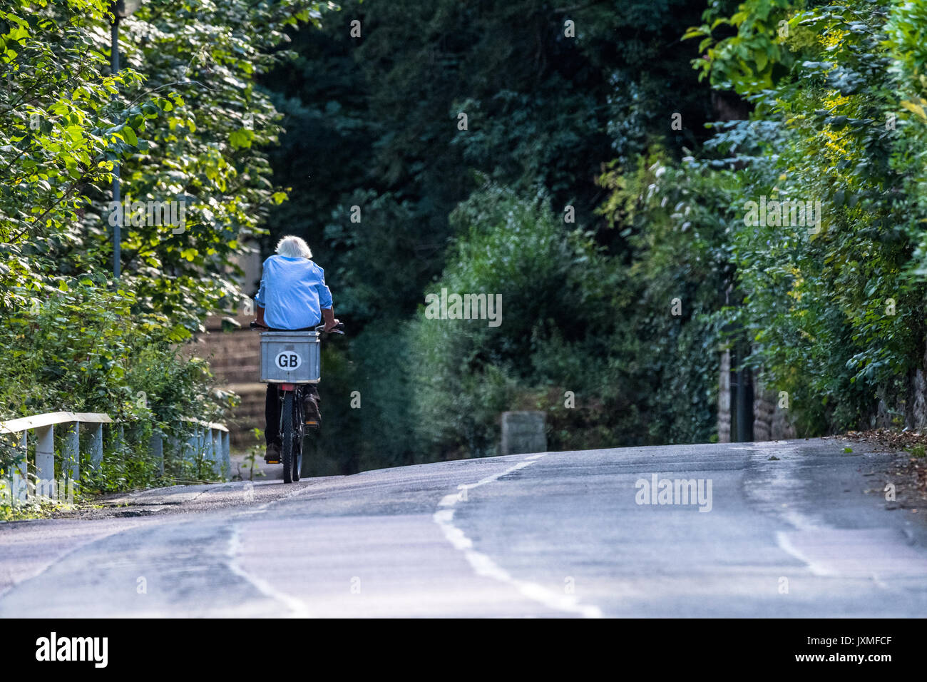 Male riding a bicycle on a country lane with G.B. sticker. Stock Photo