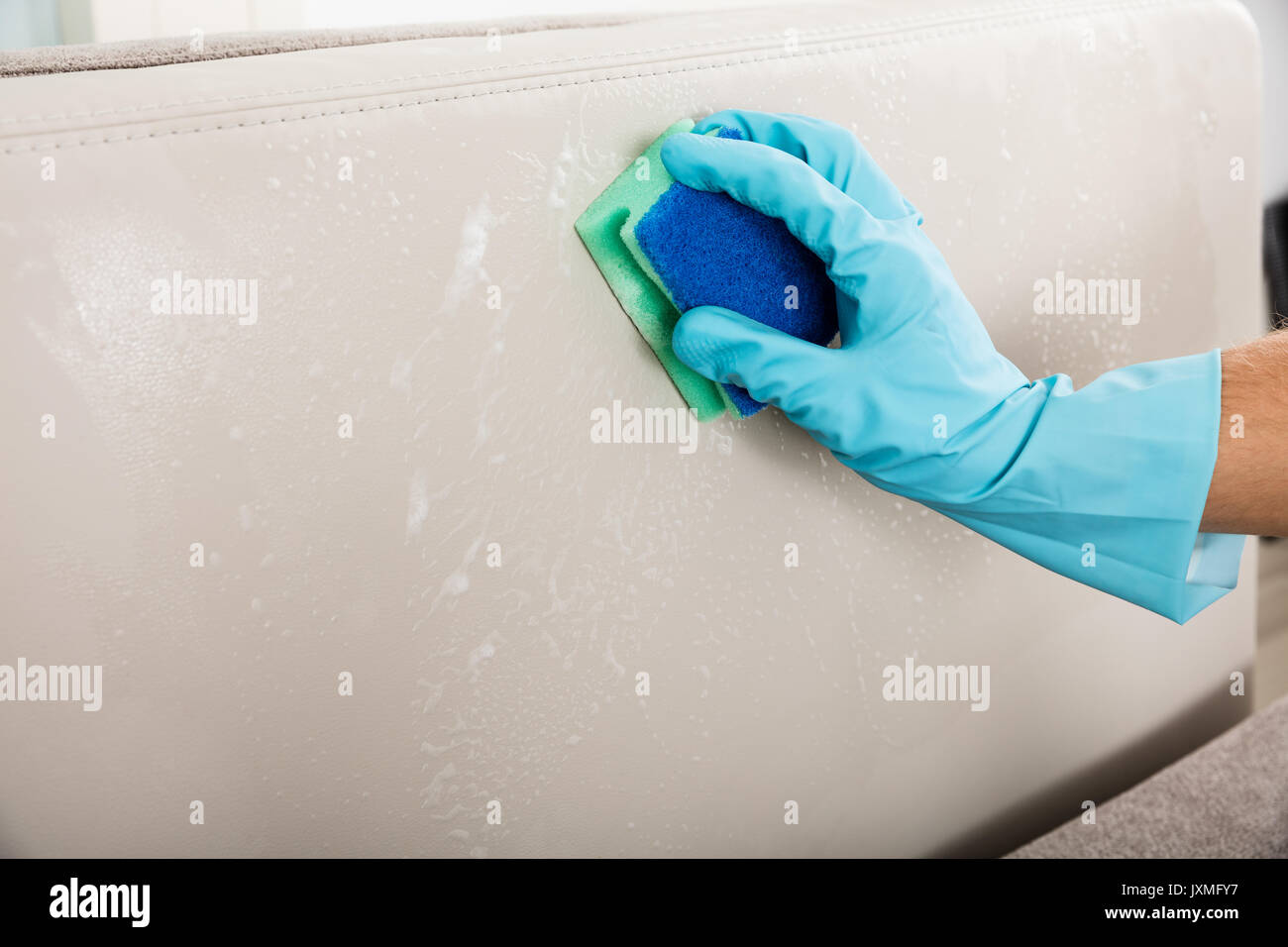 Closeup Of Person's Hand Wearing Gloves Cleaning Cushion Sofa