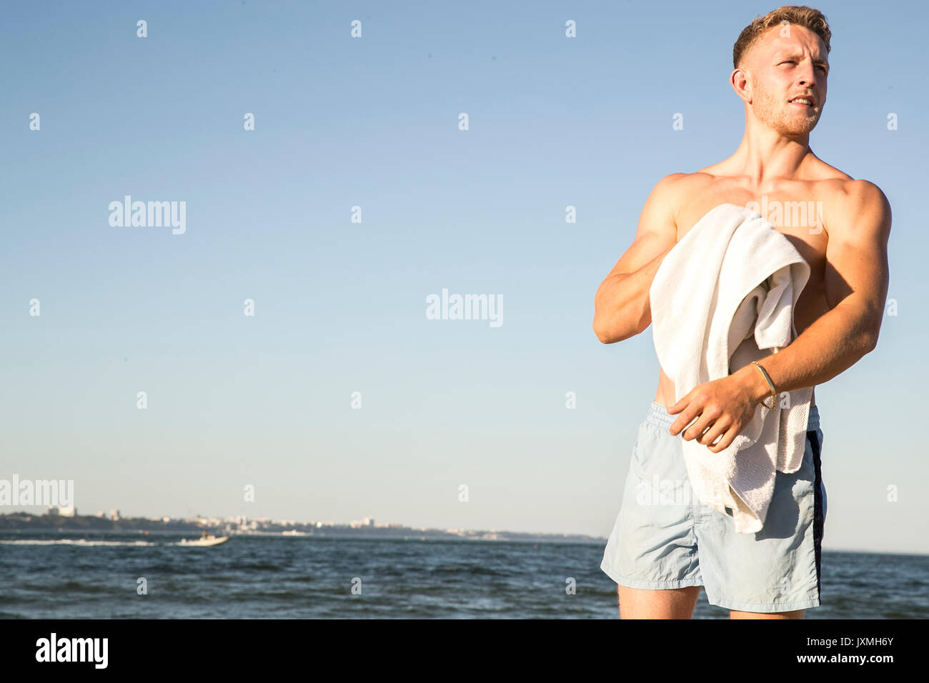 Young male swimmer drying himself with towel on beach Stock Photo