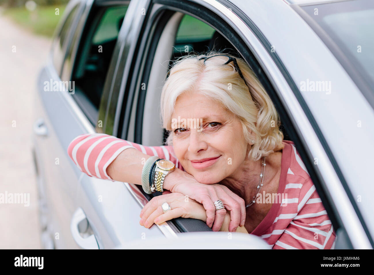Portrait of mature woman looking out of car window on roadside Stock ...