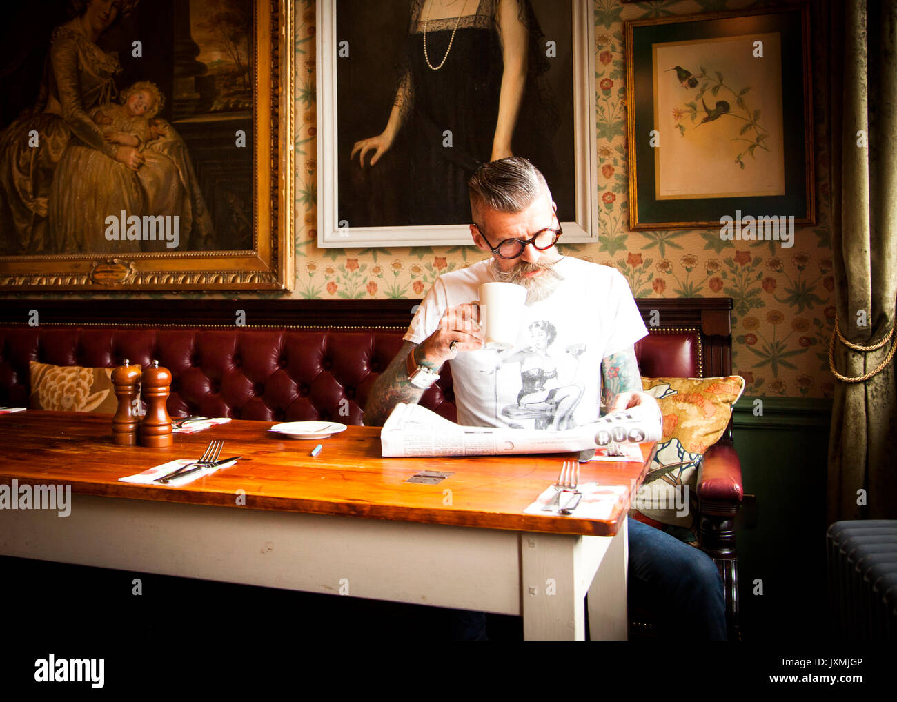 Quirky man reading newspapers in bar and restaurant, Bournemouth