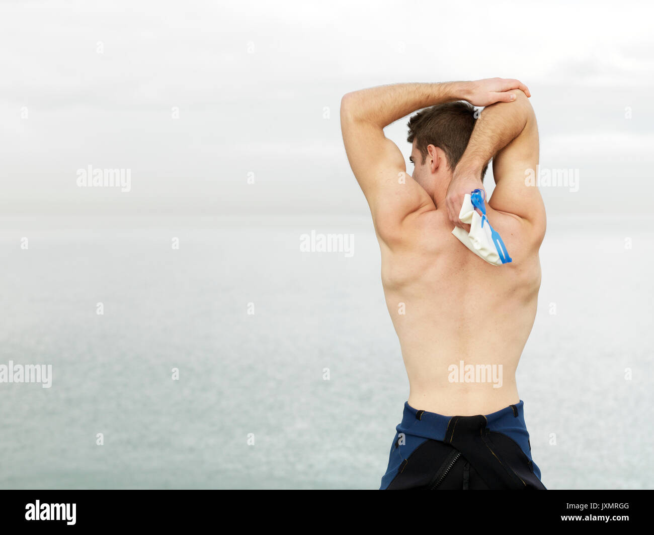 Rear view of bare chested man warming up, stretching arms, Melbourne, Victoria, Australia, Oceania Stock Photo