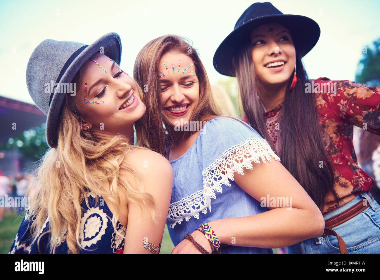 Three young female friends in fedoras dancing at festival Stock Photo