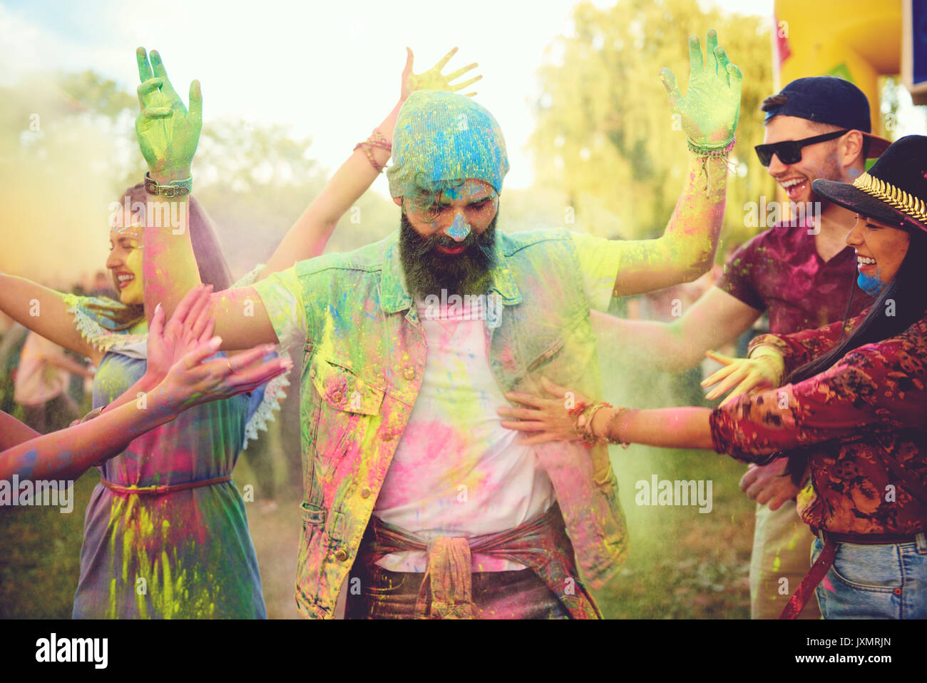 Young adult friends throwing coloured chalk powder and dancing at