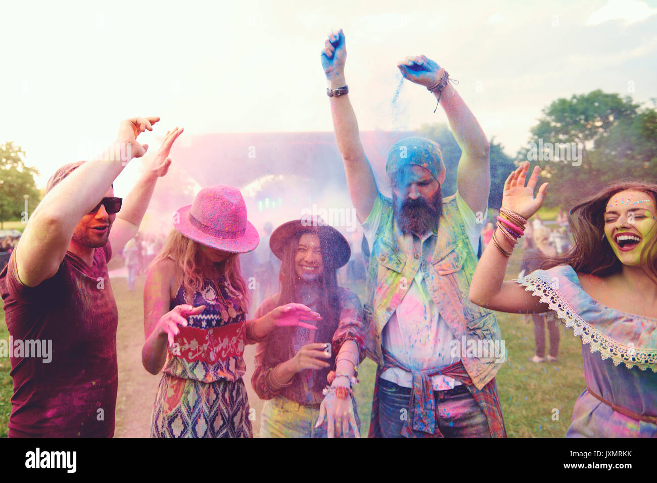 Young adult friends dancing and throwing coloured chalk powder at