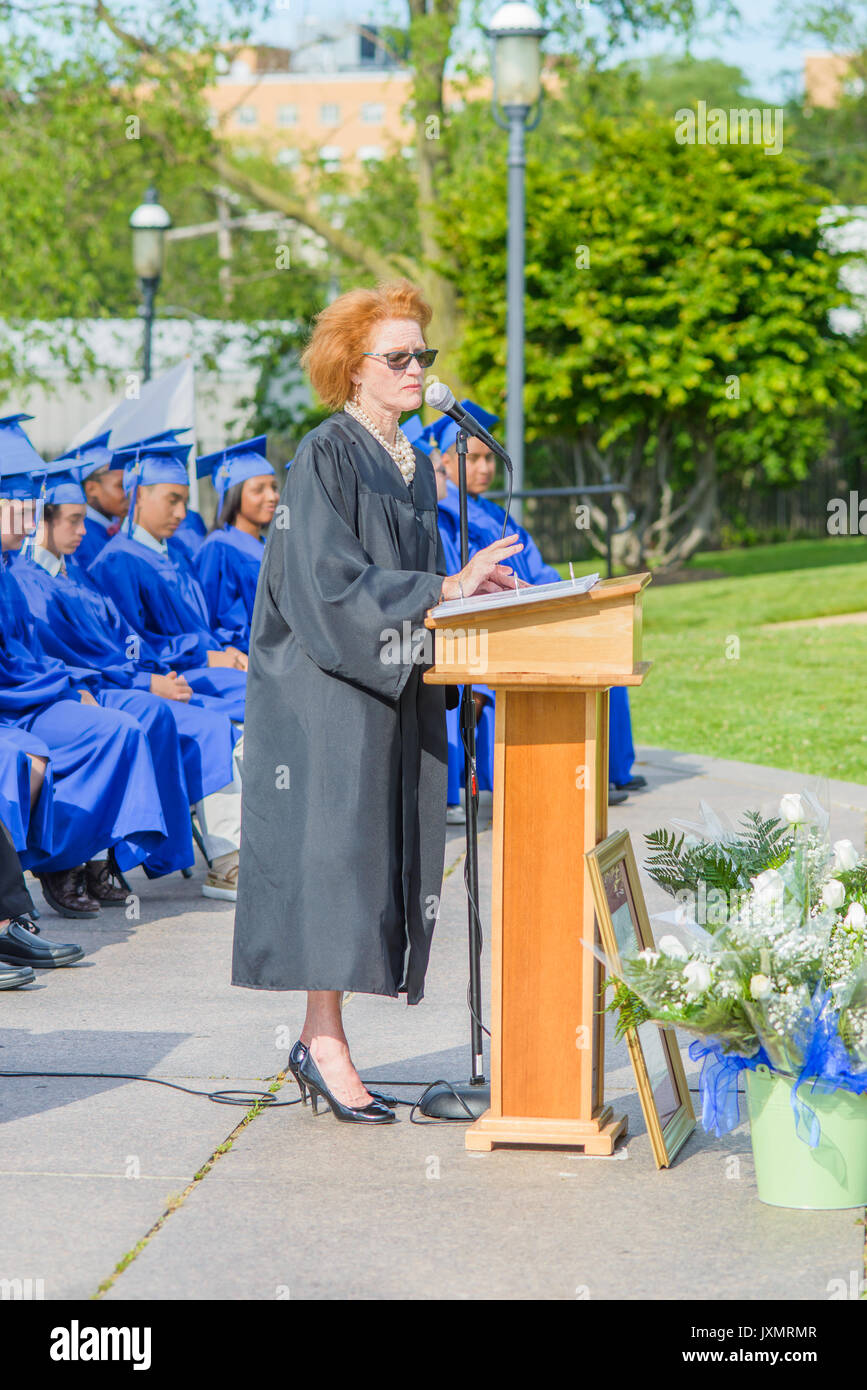 Principle standing at podium, giving speech, on graduation day. Students sitting in rows behind Stock Photo