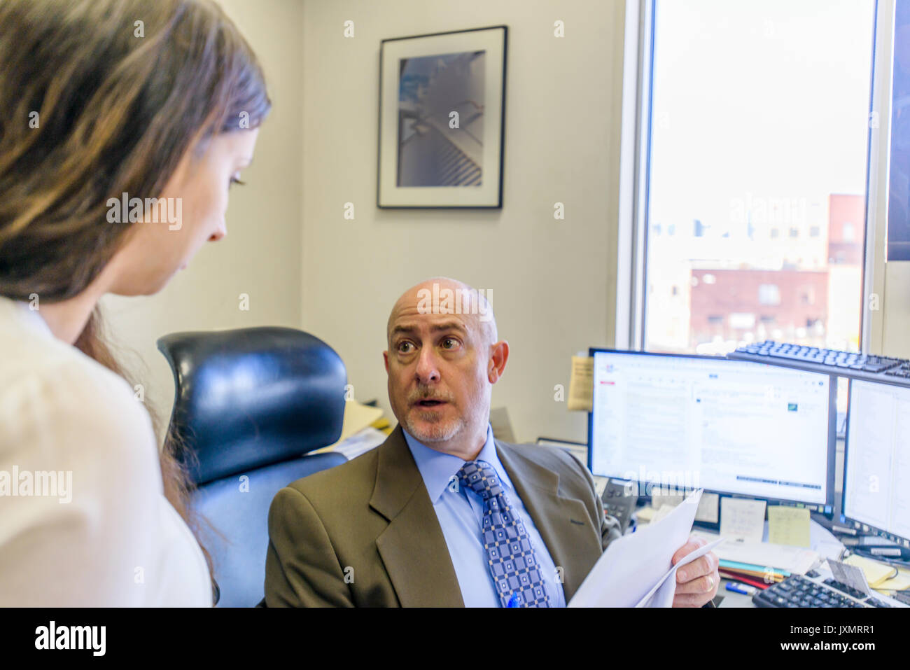 Over shoulder view of manager having discussion with office worker at ...