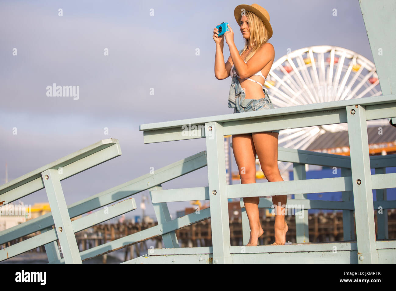Young woman taking photographs from beach hut, Santa Monica, California, USA Stock Photo