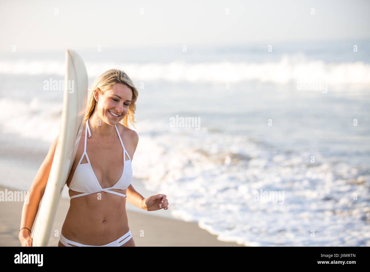 Young female surfer carrying surfboard along beach, Santa Monica, California, USA Stock Photo