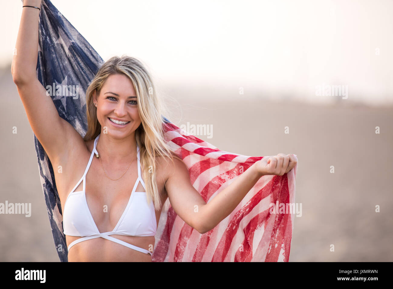 Portrait of young woman in bikini top holding up american flag, Santa Monica, California, USA Stock Photo