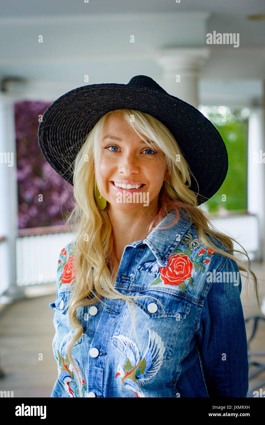 Portrait of blond haired woman in cowboy hat on porch Stock Photo