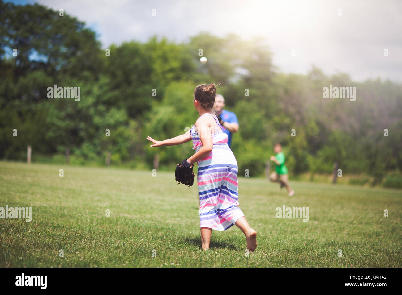 Girl playing baseball on field Stock Photo