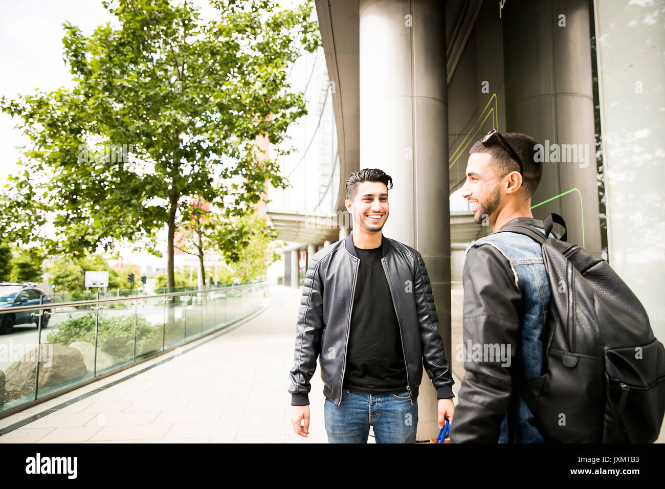 Two young men, standing in street, smiling Stock Photo