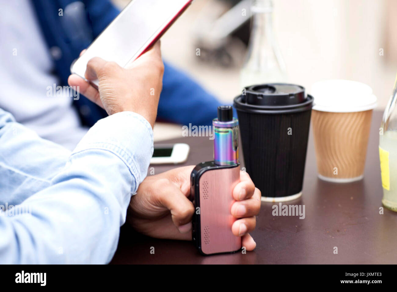 Cropped view of man holding smartphone and vape Stock Photo