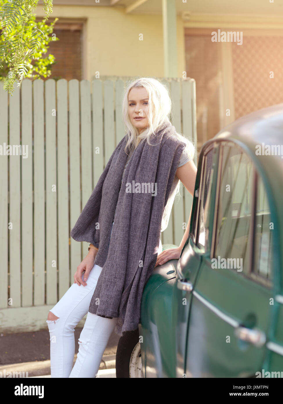 Young woman leaning against car, towel around neck Stock Photo