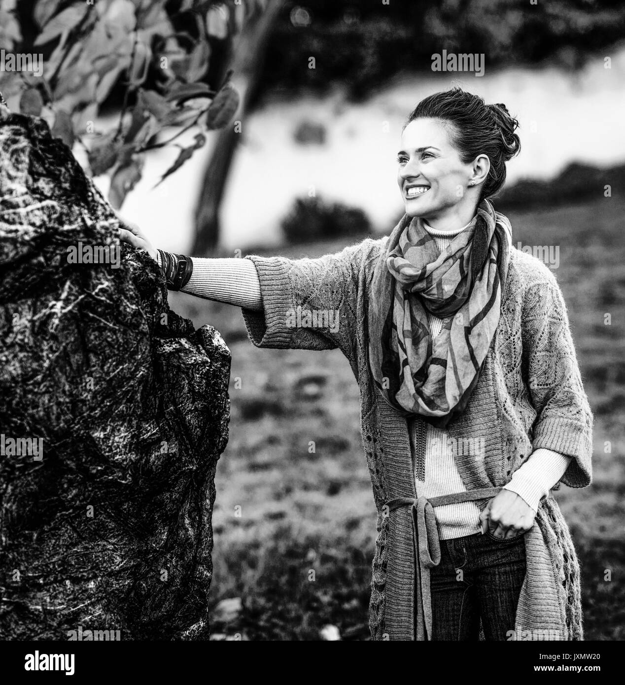 Portrait of happy young woman standing in autumn park in evening Stock Photo