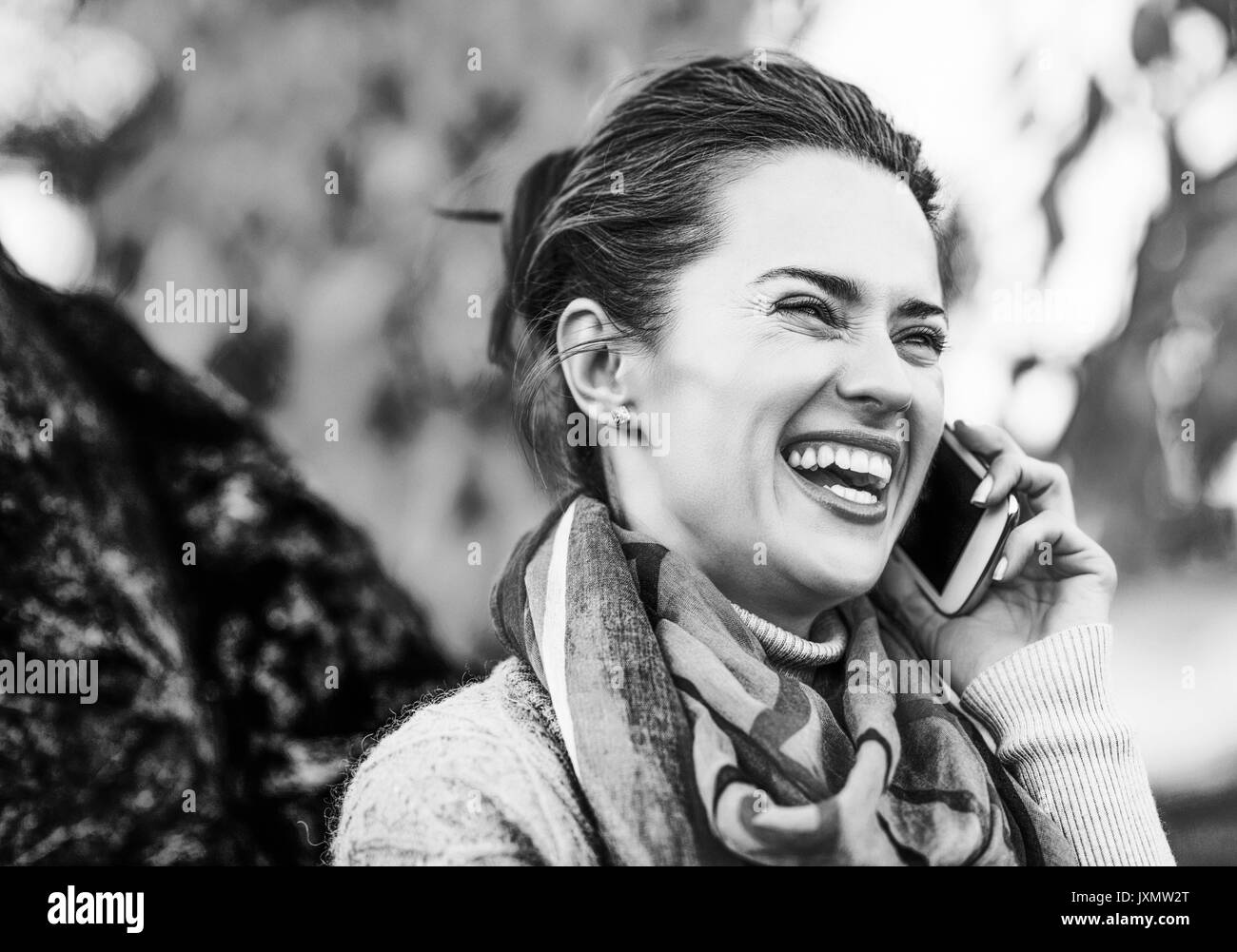 Portrait of happy young woman in autumn outdoors in evening talking mobile phone Stock Photo