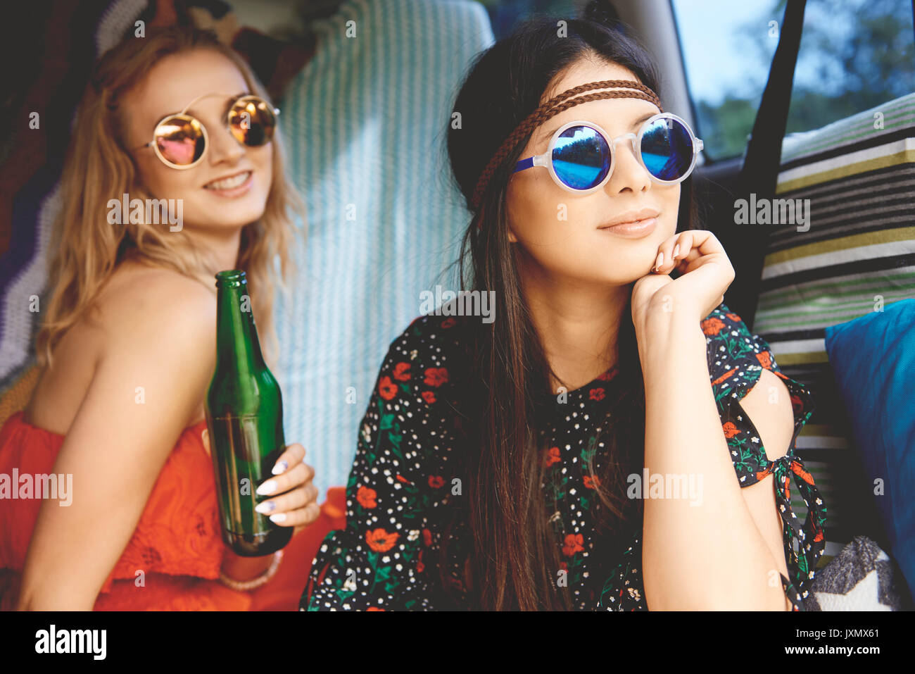 Two young boho women wearing sunglasses in recreational van Stock Photo