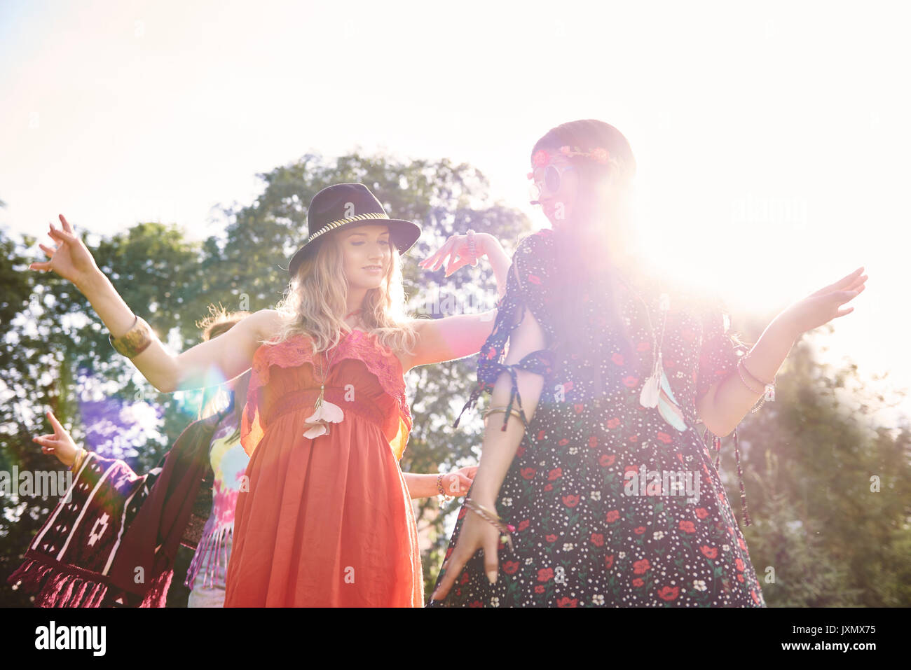 Two young boho women dancing in sunlight at festival Stock Photo