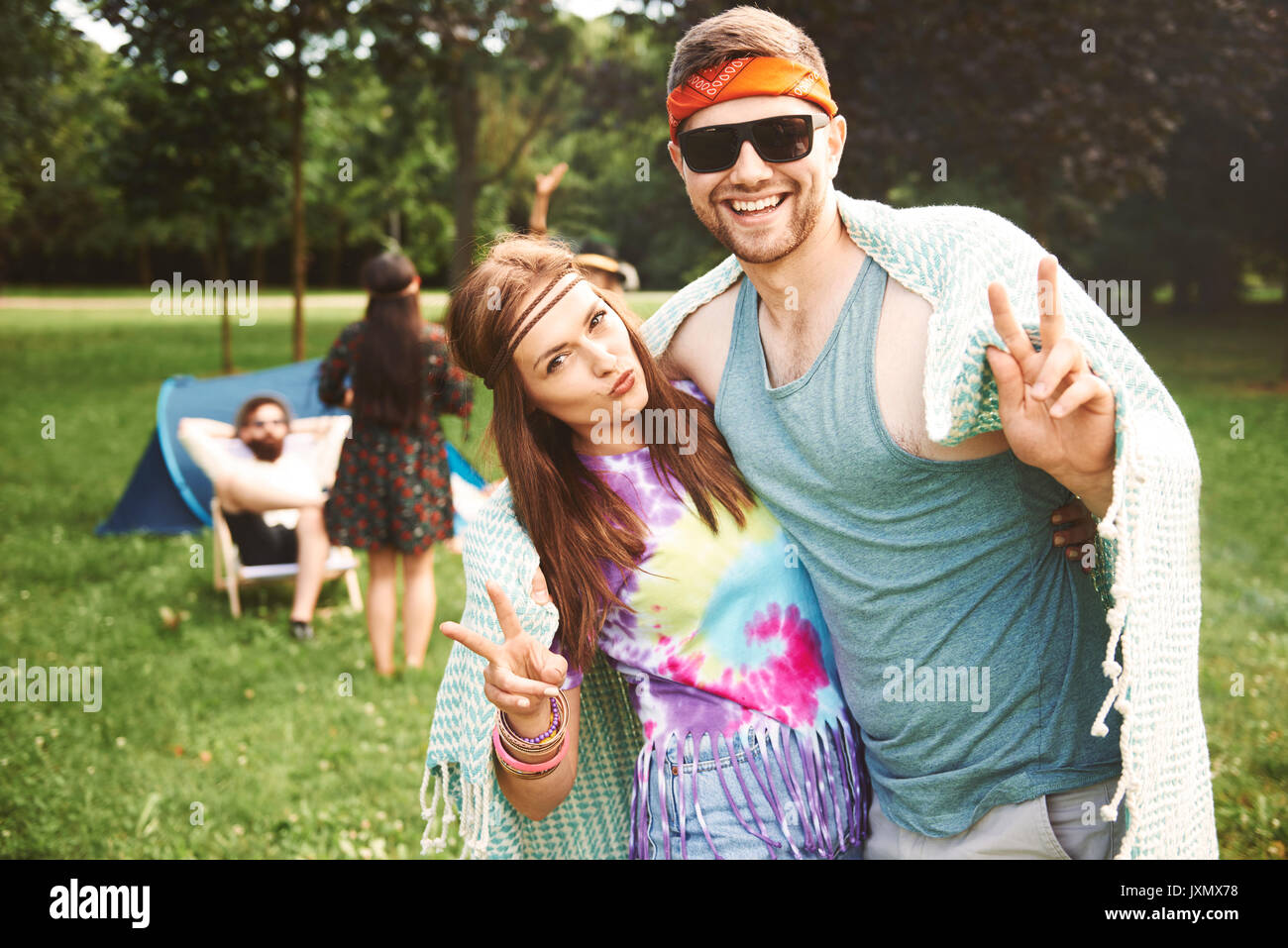 Portrait of young boho couple making peace signs at festival Stock Photo