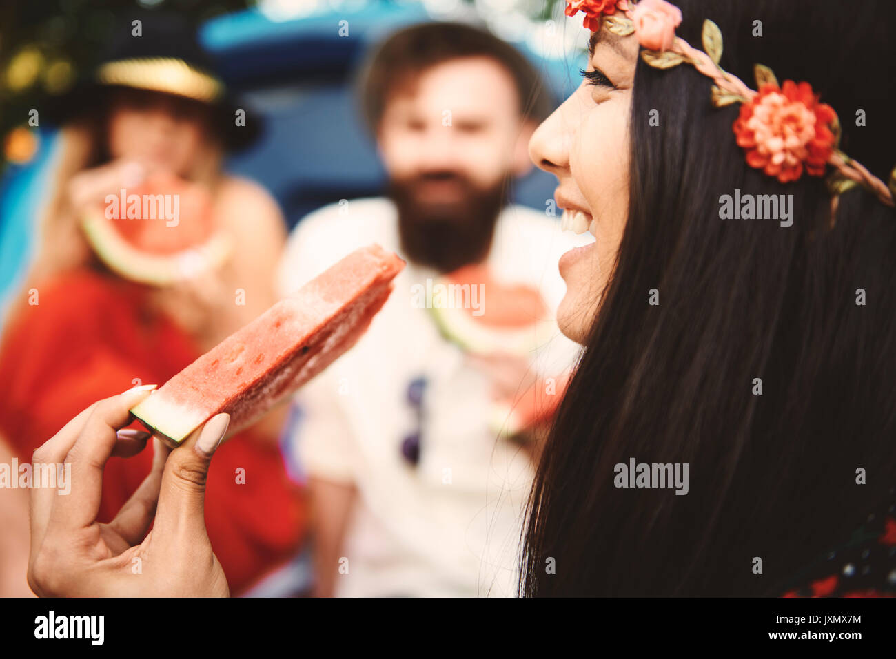 Young boho woman eating melon slice at festival Stock Photo