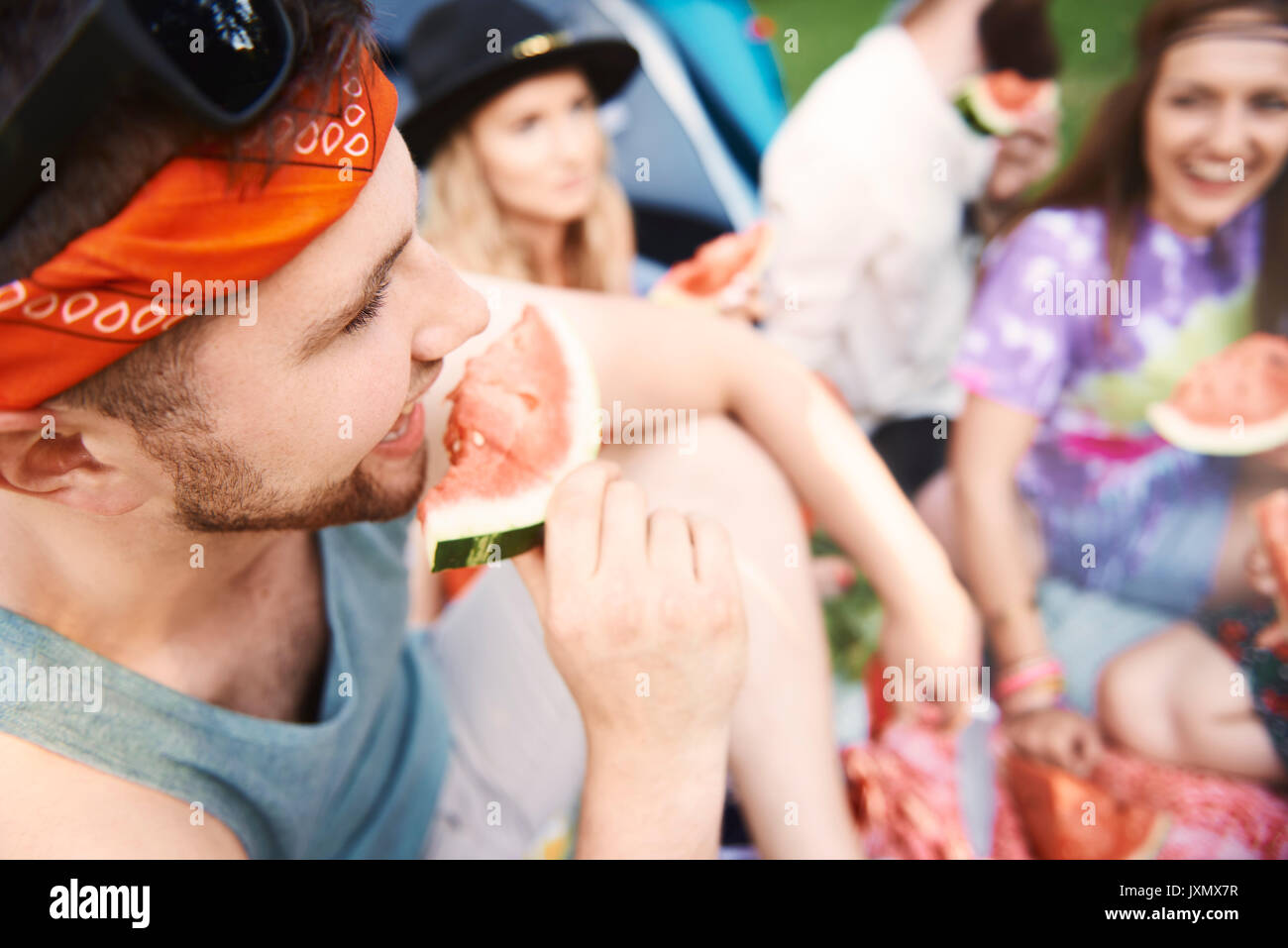 Young boho adult friends eating melon slices at festival Stock Photo