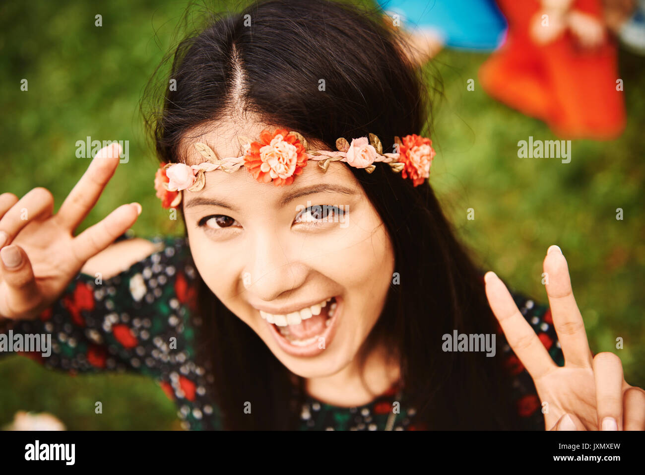 Portrait of young boho woman making peace sign at festival Stock Photo
