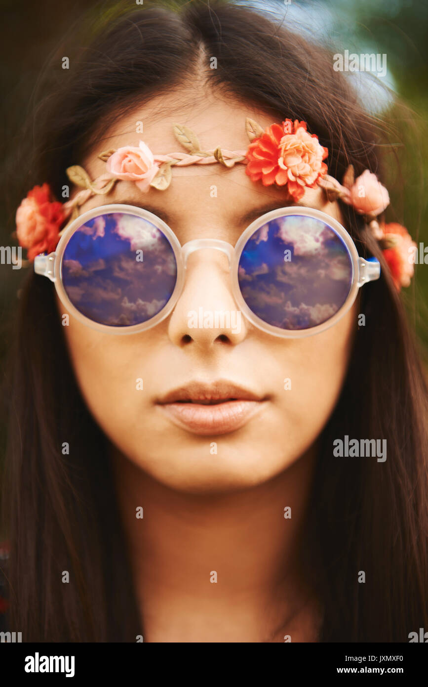 Portrait of young hippy woman in floral headband and sunglasses at festival Stock Photo