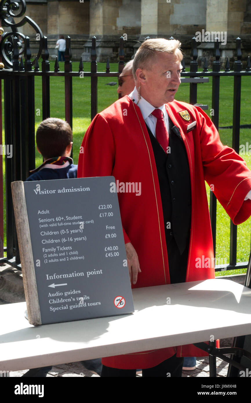Man dressed in gown at the entrance to Westminster Palace, 20 Deans Yd, Westminster, London SW1P 3PA, UK with price list for visitors Stock Photo
