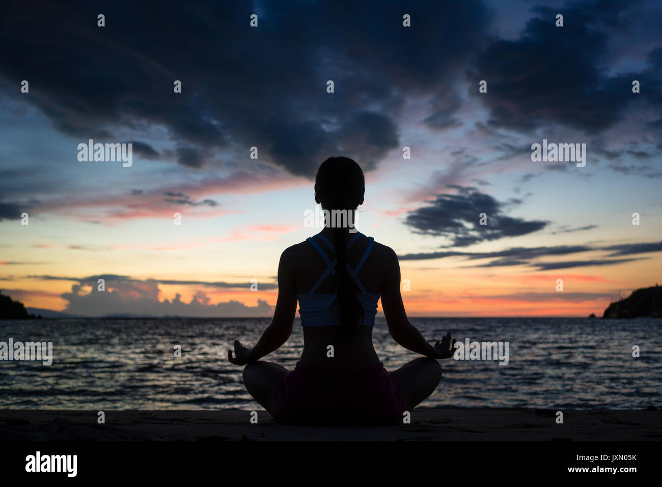 Fit woman sitting in lotus position while practicing yoga on the Stock ...