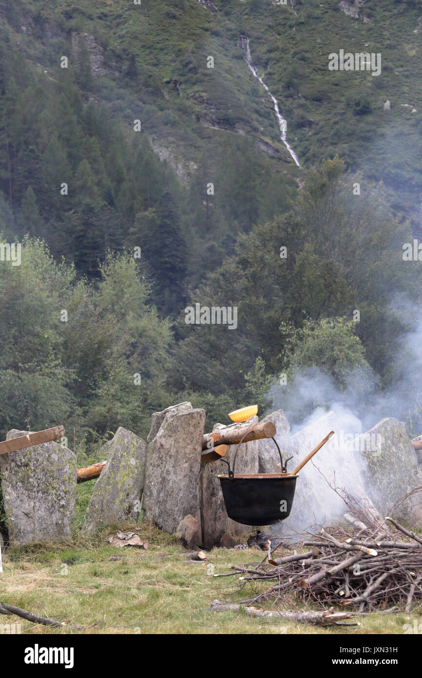 Italian cornmeal polenta (mush) being cooked on slow flame in a pot on a wood and coal bonfire