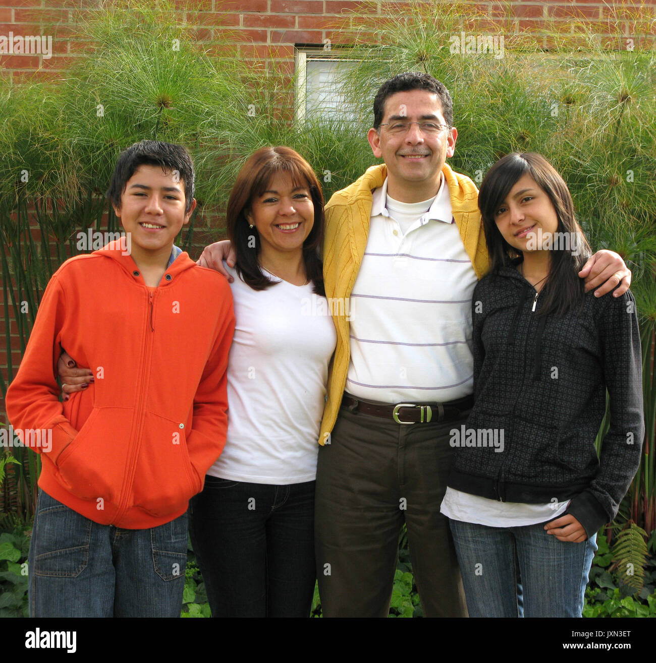 Family from four stands on grass against house Stock Photo