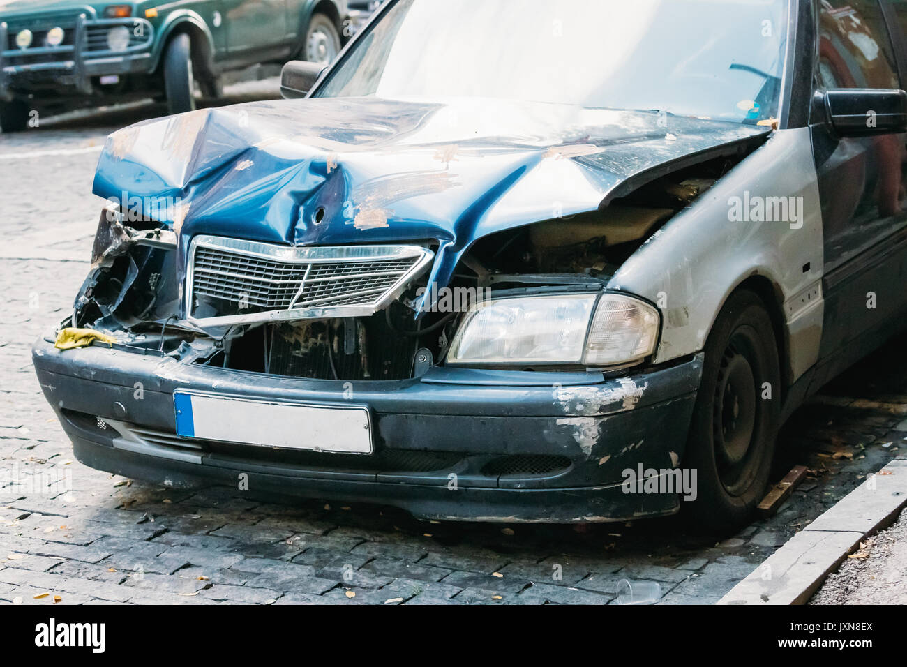 Close Up Of Broken Bumper And Bonnet Or Hood Of Luxury Car Scratched With Damages. Abandoned Car After Accident In City Street Stock Photo