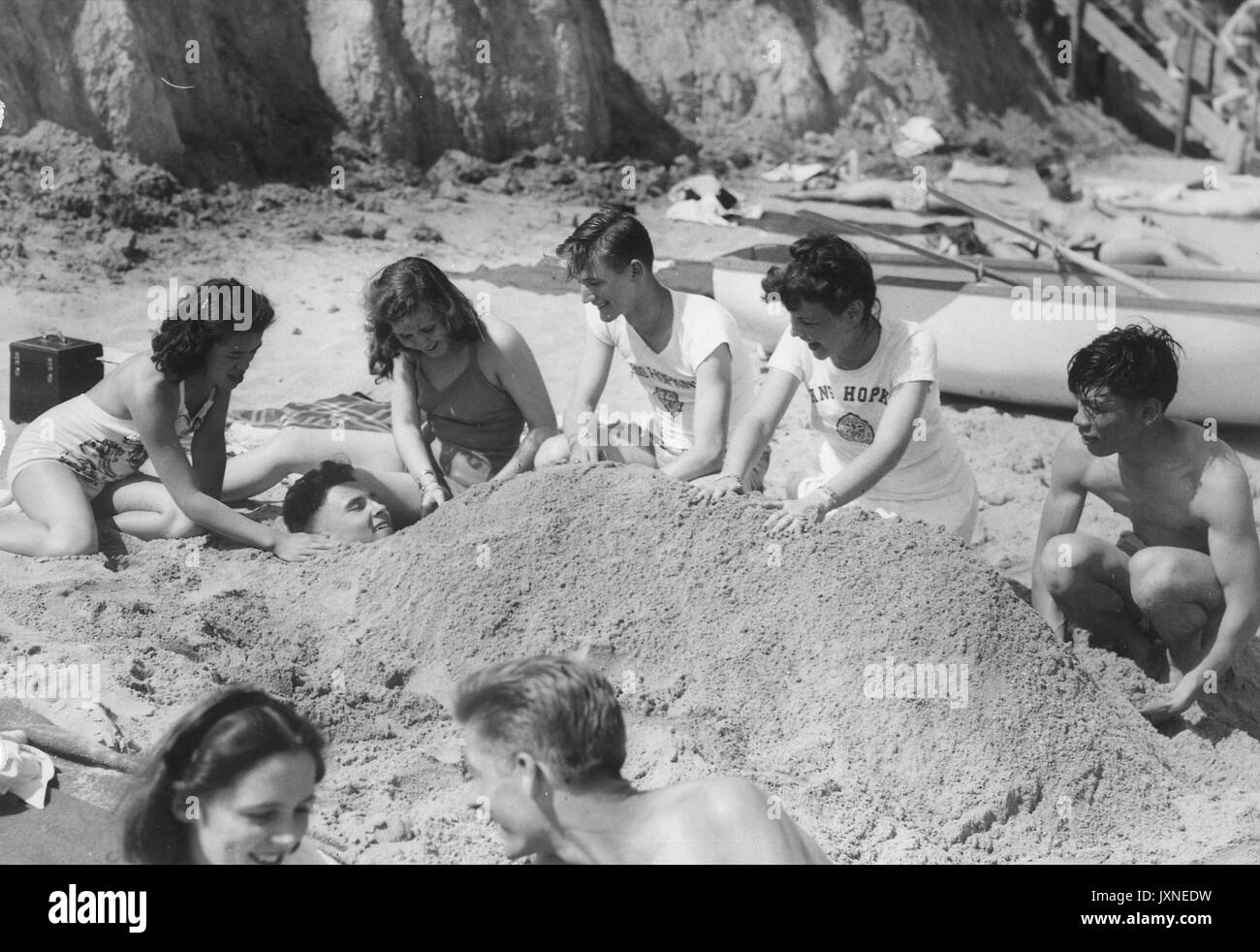 Student Life, Beach Party, Senior Week Candid shot of students and their girlfriends burying a student in the sand at Triton beach, 1947. Stock Photo
