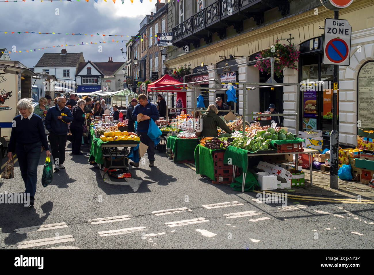 Regular weekly market in Knaresborough North Yorkshire busy crowd and fruit and vegetables on display. Stock Photo