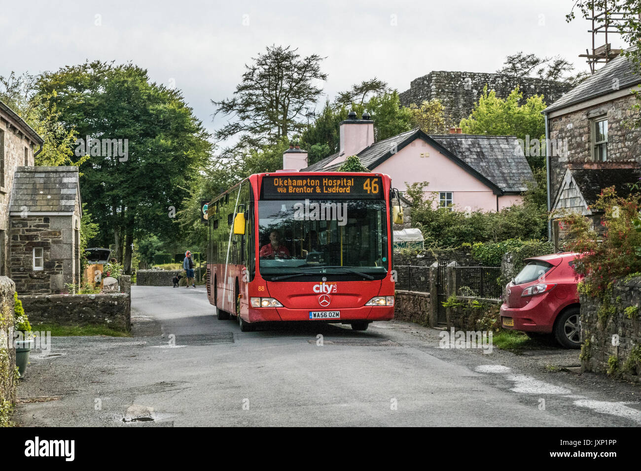 A man driving the number 46 bus to Okehampton, along the main street of Lydford village, near Okehampton, Devon, England, UK. Stock Photo