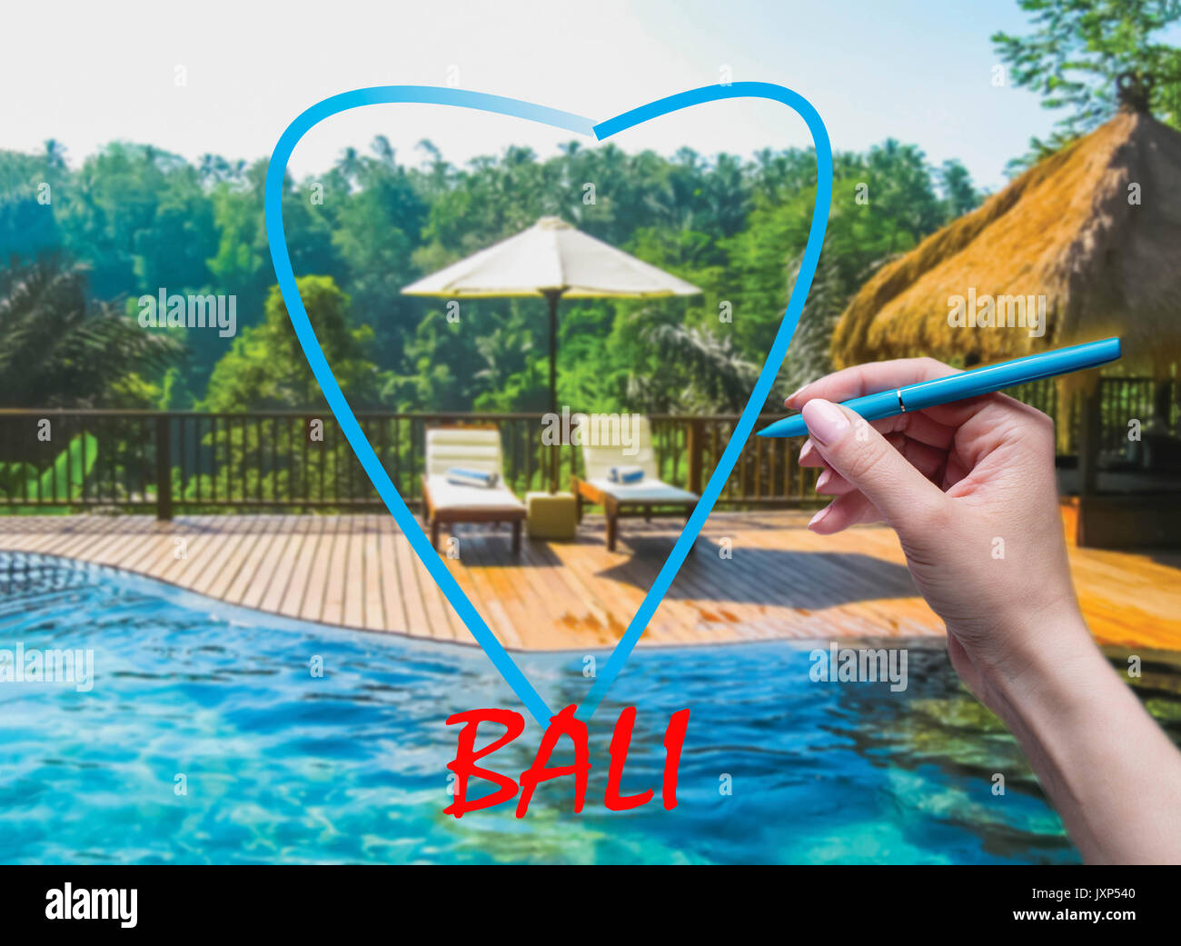 The female hand with pen drawing heart and Bali background Stock Photo