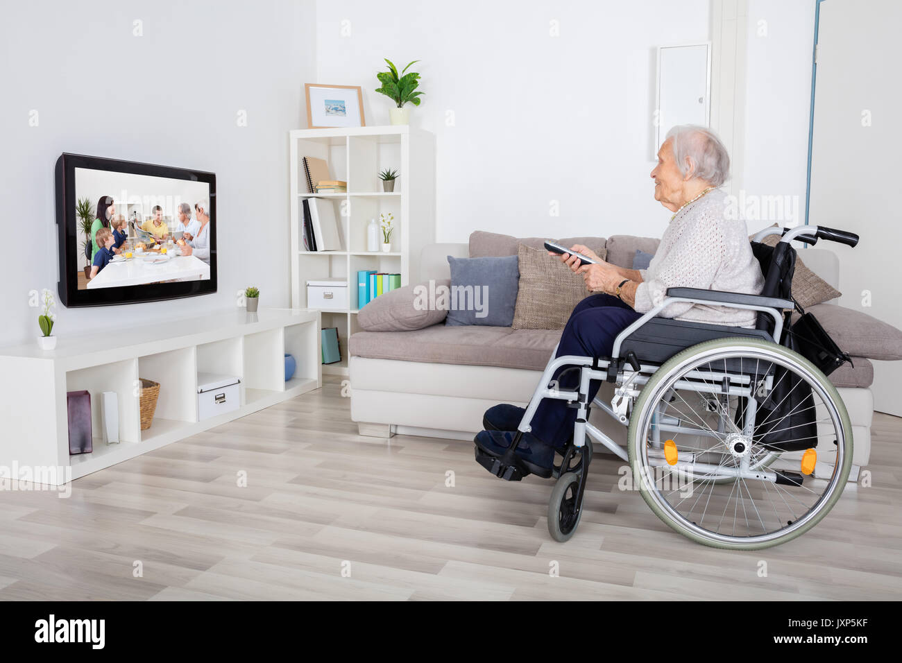 Grandmother On Wheelchair Watching Movie On Television At Home Stock Photo