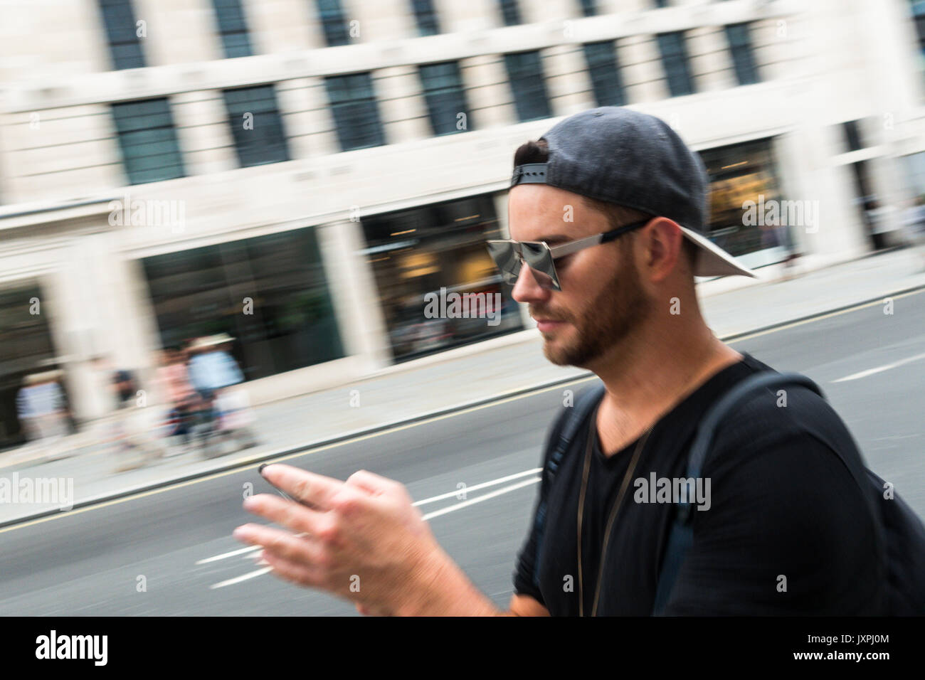 Fulfill radius Patience Man walking and texting with phone and reversed baseball cap with motion  blur Regent Street Saint James's St. James's, London SW1Y UK Stock Photo -  Alamy