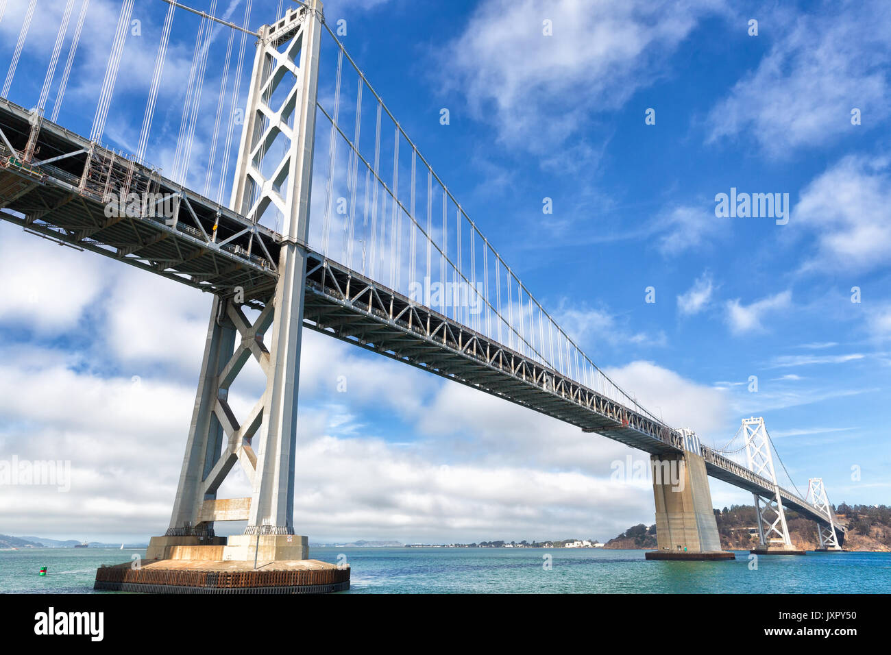 San Francisco Oakland Bay Bridge. Wide angle view from water level. Looking toward Treasure Island. Blue sky with beautiful white clouds. Stock Photo