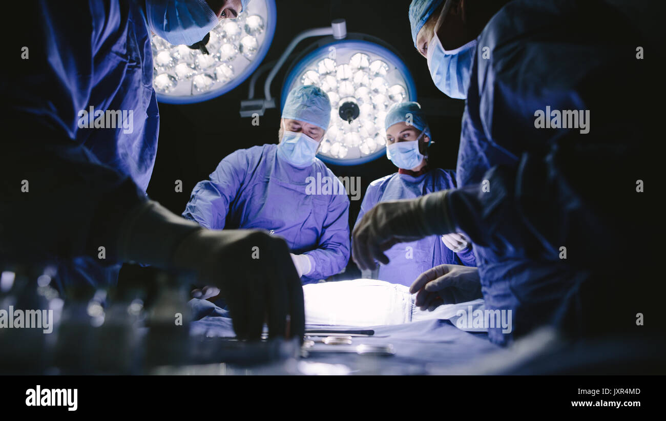 Team of surgeons performing surgery in operation theater. Group of doctors in hospital operating theatre. Stock Photo