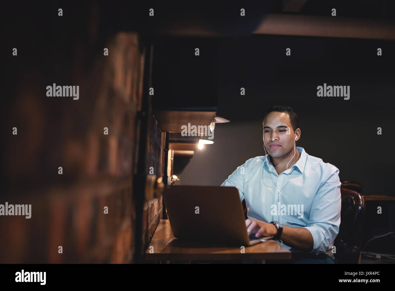 Young man working at the laptop late at night. African businessman working overtime in the office. Stock Photo