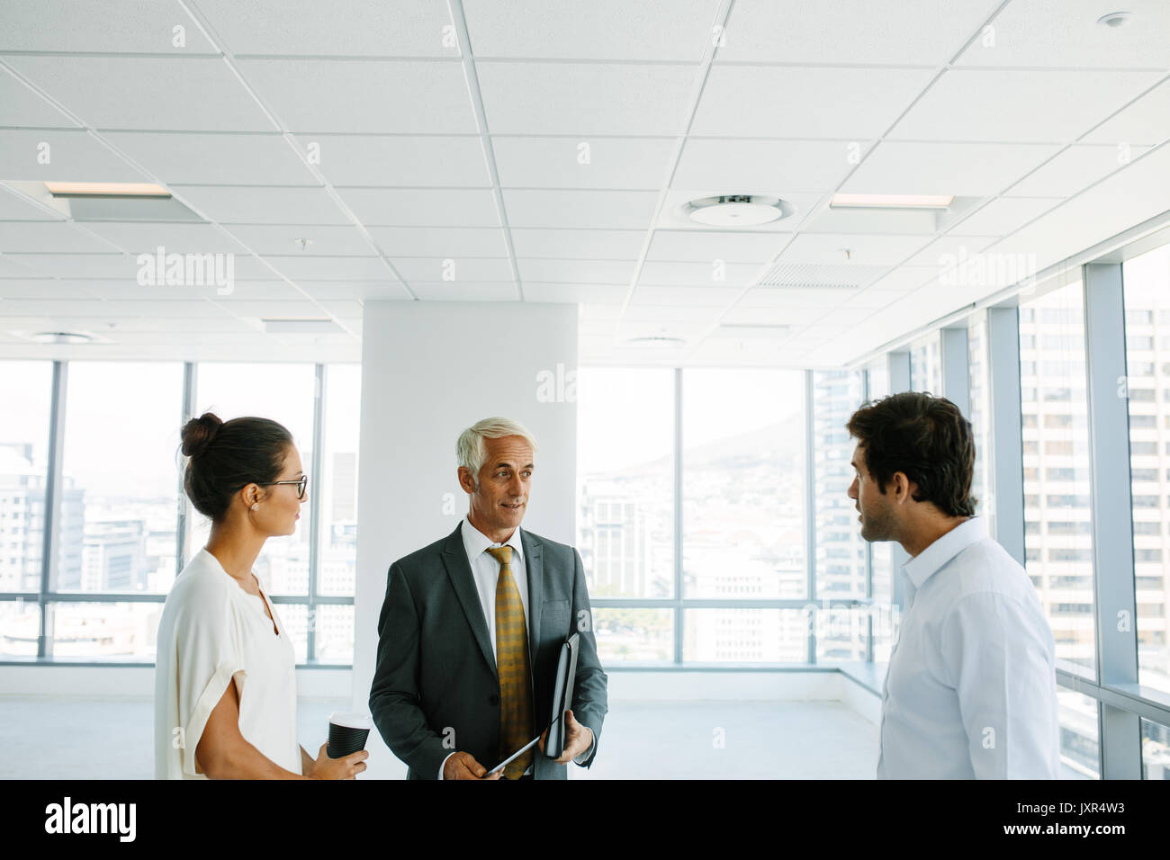 Business people discussing with real estate agent at empty space. Estate broker and clients talking inside a new office site. Stock Photo