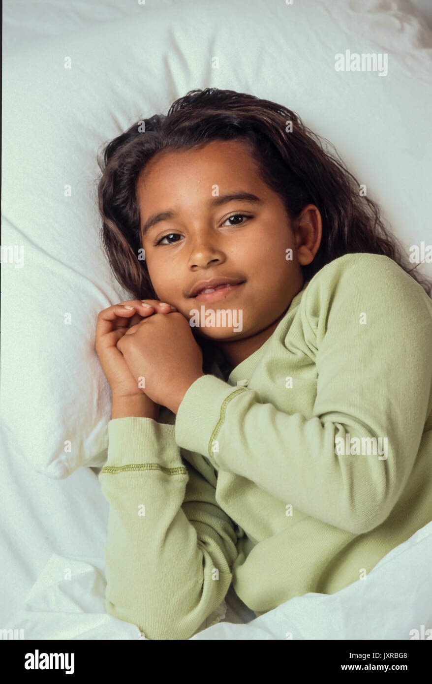 Bedtime for young Girl  7-10 year old  in bed ready to pray and go to sleep African American/Caucasian Stock Photo