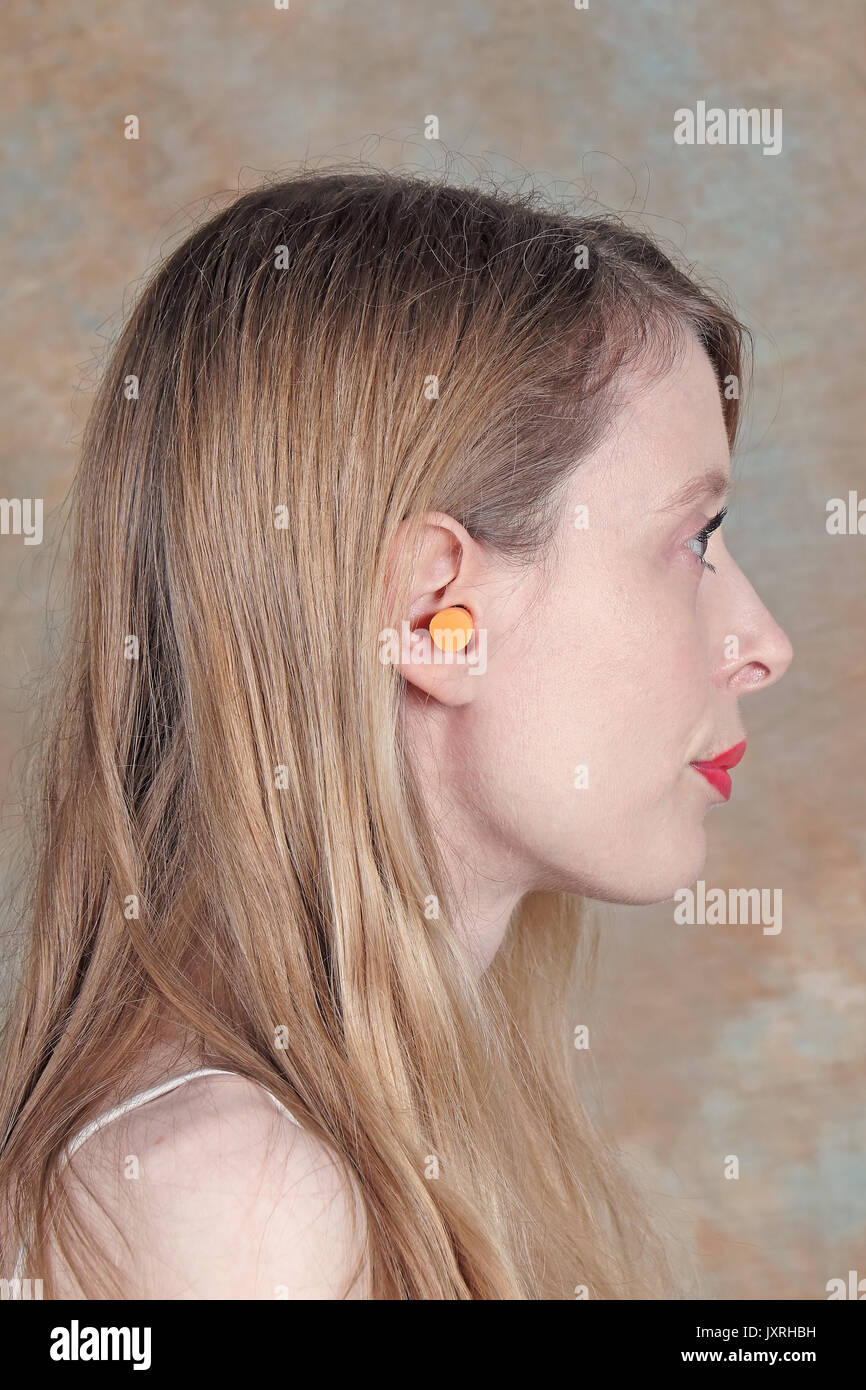 Woman wearing ear plug as noise cancellation Stock Photo