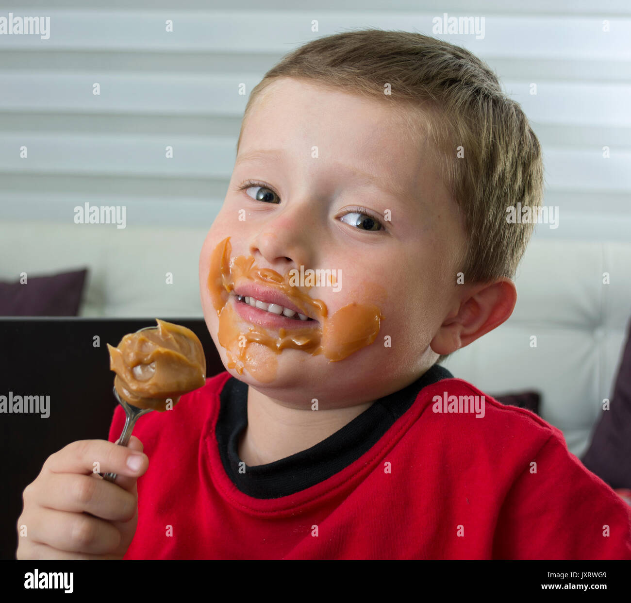 Boy eating chocolate in spoon Stock Photo Alamy