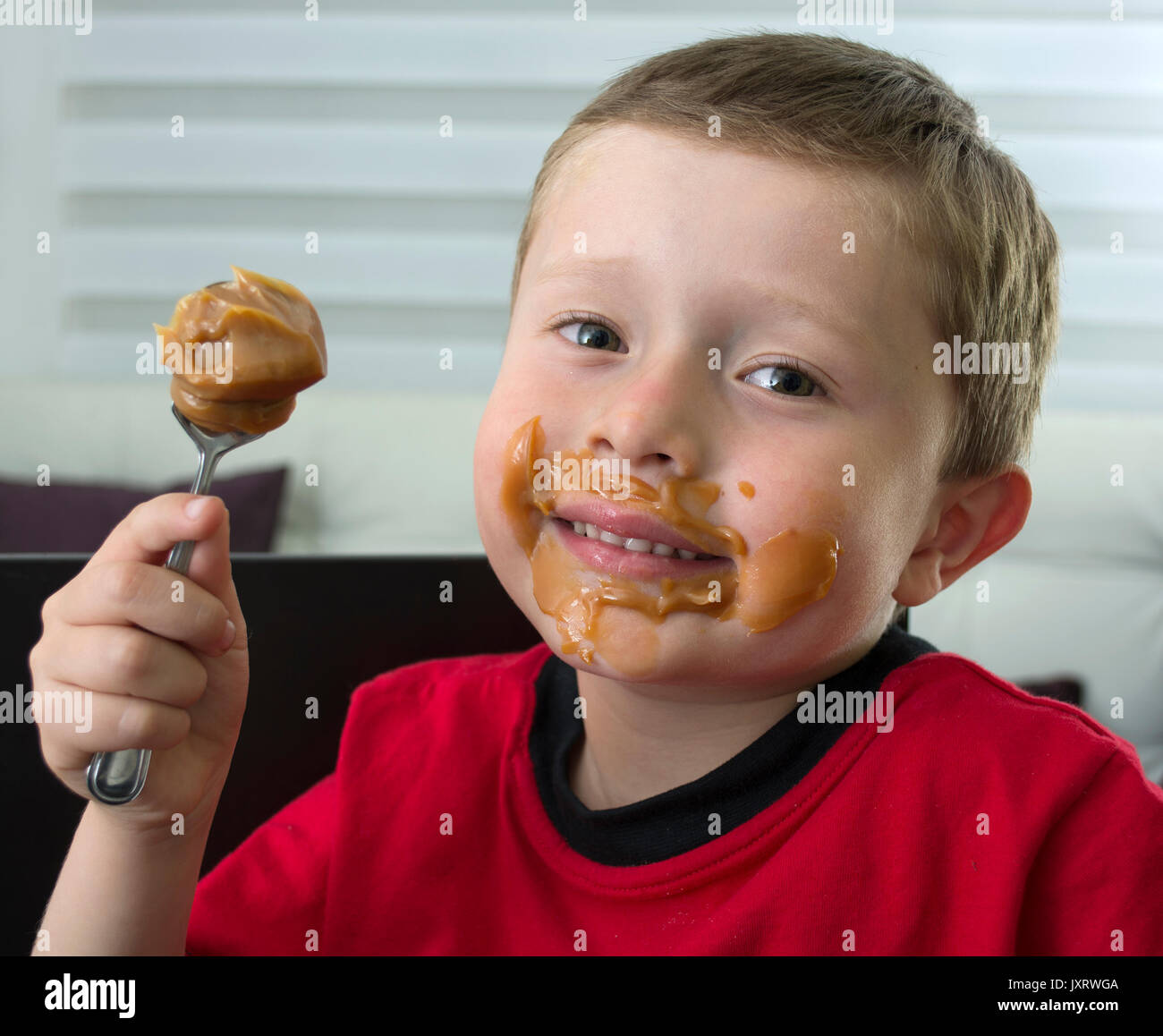 Boy eating chocolate in spoon. Stock Photo