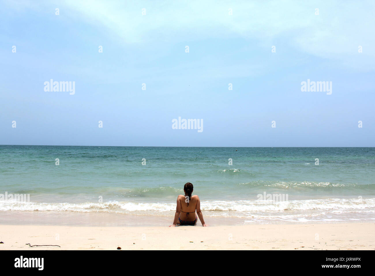 Girl standing back on the summer beach Stock Photo