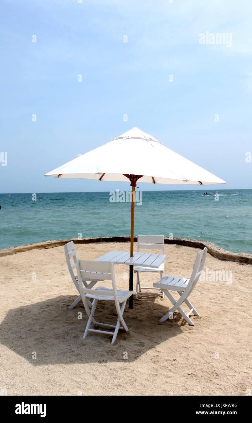 View of four chairs and umbrella on the beach Stock Photo
